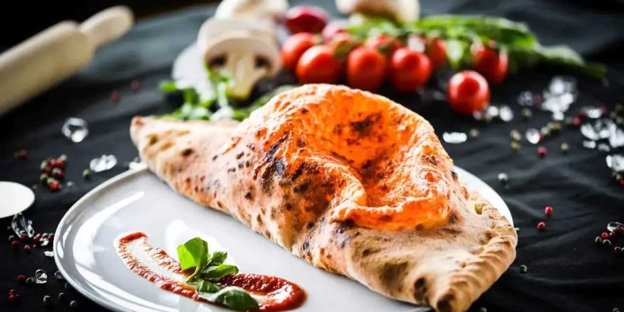 Ein köstlicher, original italienischer Calzone, goldbraun gebacken, mit Tomatensoße und Basilikum garniert.