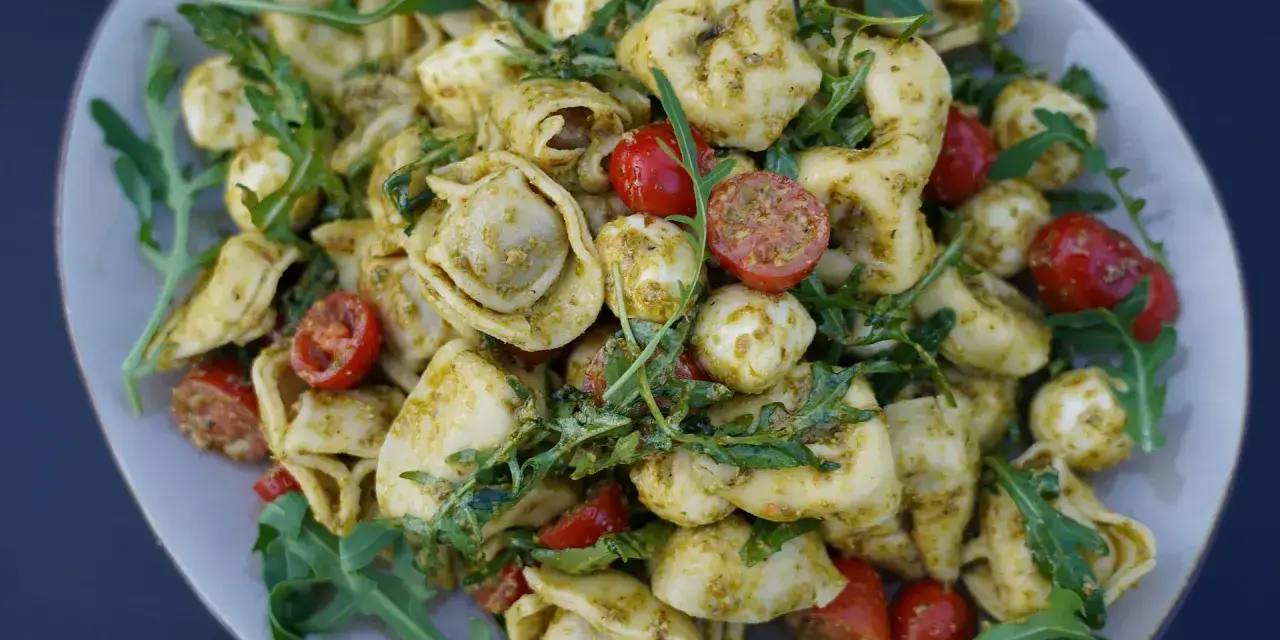 Tortellini Salat mit Rucola, Kirschtomaten und Mozzarella-Kugeln, alles in Pesto geschwenkt. Ein leichter Genuss!