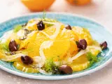 Erfrischender orangensalat sizilianisch mit Fenchel und dunklen Oliven auf einem blauen Teller.