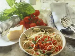 Spaghetti mit frischen Kräutern und gehackten Tomaten aus der Dose. Dazu ein Stück Parmesan, frische Tomaten und ein Grater. Perfekt für einfache Rezepte mit gehackten Tomaten aus der Dose.