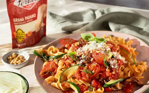 Fusilli mit Tomaten, Zucchini und Pinienkernen, bestreut mit frisch geriebenem Grana Padano. Perfekte parmesan verwendung für ein leichtes Gericht.