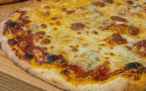 Eine köstliche quattro formaggi Pizza mit geschmolzenem Käse und knusprigem Rand auf einem Holzbrett.