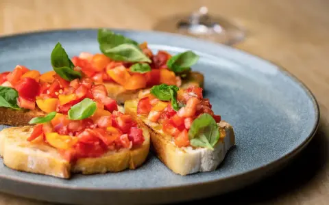 Drei Scheiben geröstetes Brot, belegt mit frischen Tomaten und Basilikum. Ein authentisches rezept bruschetta original italienisch.