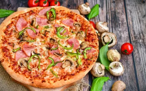 Eine leckere Pizza mit Schinken, Pilzen und Paprika. Die Frage "wie viel Kalorien hat eine Pizza" bleibt bei diesem Anblick offen.