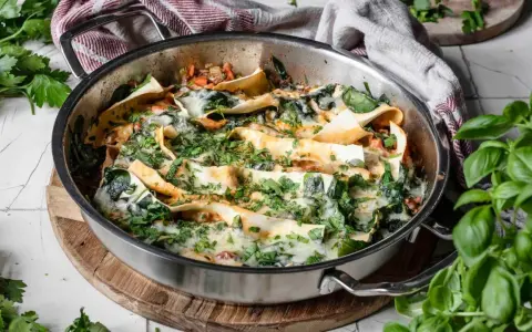 Lasagneplatten vorkochen ohne verkleben: Ein köstliches Gericht mit Spinat und Käse in einer Pfanne, garniert mit frischen Kräutern.