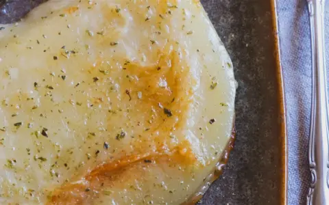 Gebratener Käse mit Kräutern, eine köstliche caciocavallo alternative, auf dunkler Platte mit Gabel.