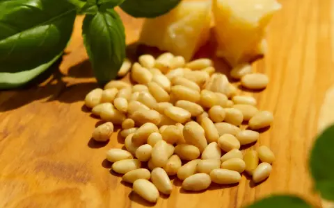Frische Pinienkerne, Basilikum und Parmesan auf Holzbrett. Achten Sie auf die Pinienkerne Haltbarkeit für Pesto.