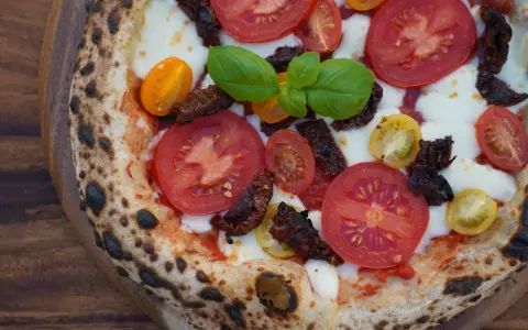 Pizza mit frischen Tomaten, Mozzarella, Basilikum und intensiven pomodorini secchi.