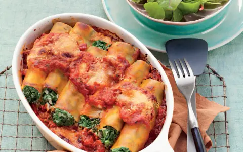 Cannelloni ricotta-spinat italienisch, überbacken mit Tomatensauce und Käse, serviert in einer Auflaufform.