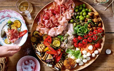 Italienische Snacks Rezepte: Eine üppige Platte mit Aufschnitt, gegrilltem Gemüse, Oliven, Tomaten und Mozzarella. Perfekt für einen Aperitif!