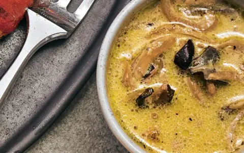 Cremige funghi sauce mit Pilzstücken in einer Schüssel, daneben eine Gabel.