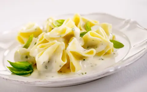 Gefüllte Pasta in cremiger Basilikum-Sahne-Sauce, garniert mit frischen Basilikumblättern. Ein Genuss für Gaumen und Auge.