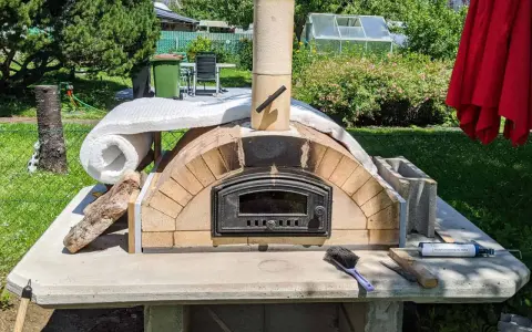 Ein selbstgebauter Pizzaofen im Garten, noch in der Bauphase, mit Isolierung und Schornstein. Bald bereit für die erste Pizza!