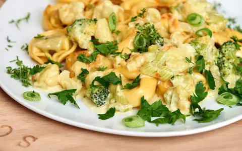 Tortellini mit Brokkoli und Blumenkohl in cremiger Sauce, garniert mit Petersilie. Lecker, wenn man Tortellini anbraten möchte.