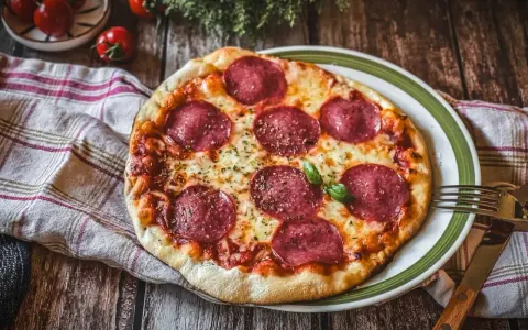 Eine köstliche Pizza Salami mit geschmolzenem Käse und frischem Basilikum auf einem rustikalen Holztisch.