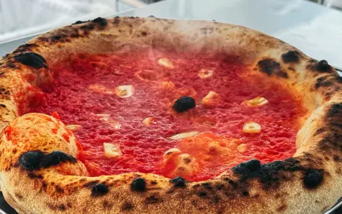 Heiß dampfende Pizza mit knusprigem Rand und leckerer marinara sauce, belegt mit Knoblauch und Oliven.