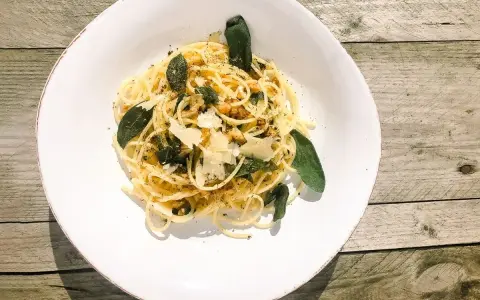 Spaghetti in Salbeibutter mit Parmesan und Walnüssen, garniert mit frischen Salbeiblättern.