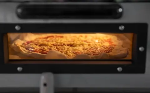 Eine Pizza mit Käse und Tomatensauce backt in einem Ofen.