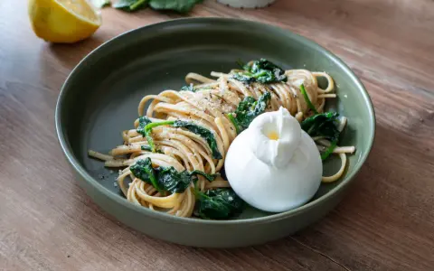 Pasta mit Spinat, Zitrone, Sahne und Parmesan, gekrönt von einem cremigen Burrata.