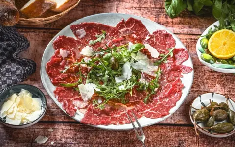 Carpaccio: hauchdünne Rindfleischscheiben mit Rucola, Parmesan und Kapern. Ein Klassiker der italienischen Küche.