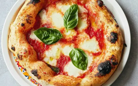 Eine original Pizza Margherita mit geschmolzenem Mozzarella, Tomatensauce und frischem Basilikum. Der Rand ist goldbraun und leicht angekohlt.