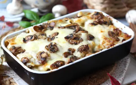 Herzhafte Lasagne al funghi mit geschmolzenem Käse und Pilzen, serviert in einer Auflaufform.