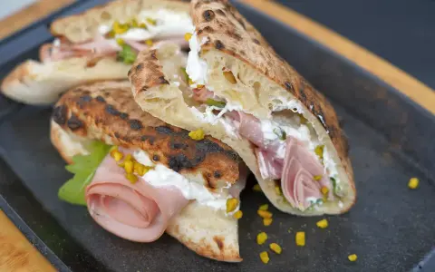 Pizza Mortadella e Pistacchio: knuspriges Brot gefüllt mit Mortadella, cremigem Käse und gehackten Pistazien. Ein Genuss!