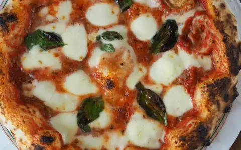 Perfekte Pizza Margherita, wie nach dem Caputo Pizzateig Rezept gemacht, mit geschmolzenem Mozzarella, Tomatensauce und frischem Basilikum.