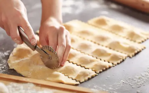 Hände schneiden mit einem Teigrädchen frische Ravioli. Das sind die besten Ravioli Rezepte zum Nachmachen.
