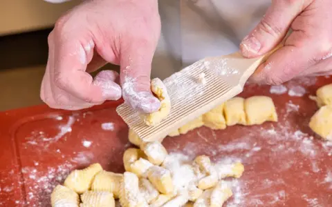 Hände formen Gnocchi mit einem Gnocchi-Brett. Köstliche italienische Gnocchi Rezepte beginnen so.