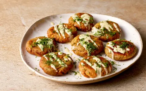 A plate of Sarde in Saor, small, round fish cakes drizzled with creamy sauce and fresh dill.
