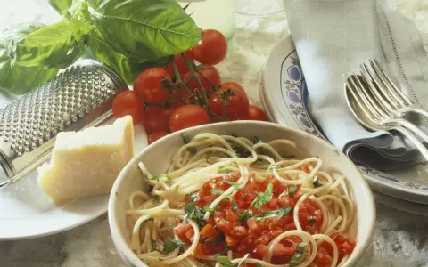 Spaghetti mit frischen Kräutern und gehackten Tomaten aus der Dose. Dazu ein Stück Parmesan, frische Tomaten und ein Grater. Perfekt für einfache Rezepte mit gehackten Tomaten aus der Dose.