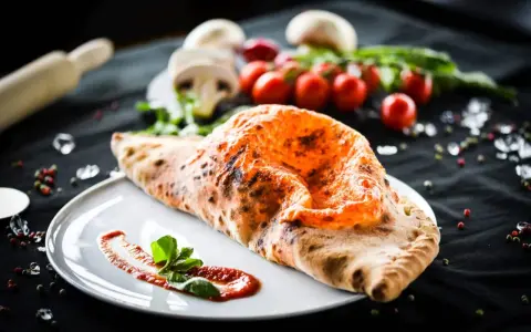 Ein köstlicher, original italienischer Calzone, goldbraun gebacken, mit Tomatensoße und Basilikum garniert.