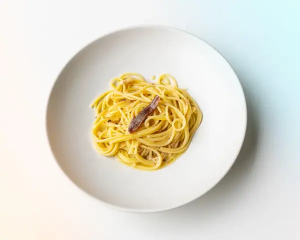 Spaghetti mit einer Sardelle, die zeigt, was sind Sardellen: kleine, salzige Fische, die Pasta verfeinern.