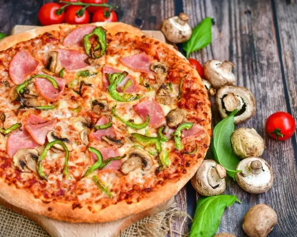 Eine leckere Pizza mit Schinken, Pilzen und Paprika. Die Frage "wie viel Kalorien hat eine Pizza" bleibt bei diesem Anblick offen.
