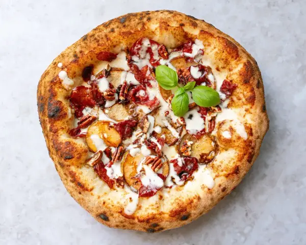 Eine köstliche Pizza aus Neapel mit Kartoffelscheiben, Speck, Nüssen und einem Hauch von Basilikum.
