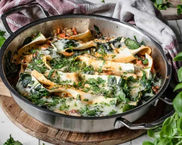 Lasagneplatten vorkochen ohne verkleben: Ein köstliches Gericht mit Spinat und Käse in einer Pfanne, garniert mit frischen Kräutern.