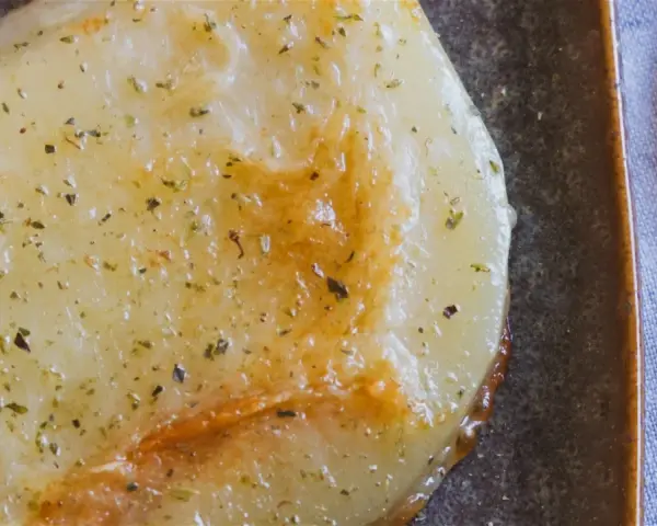 Gebratener Käse mit Kräutern, eine köstliche caciocavallo alternative, auf dunkler Platte mit Gabel.