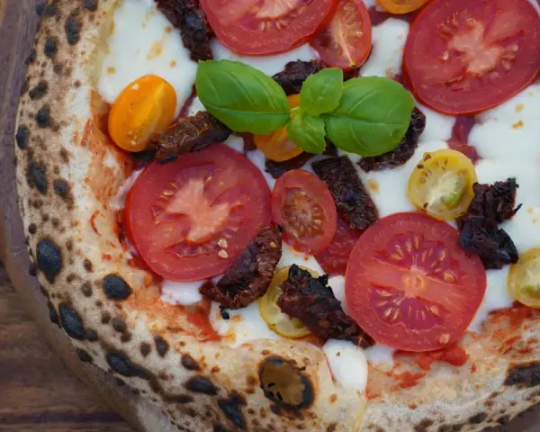 Pizza mit frischen Tomaten, Mozzarella, Basilikum und intensiven pomodorini secchi.
