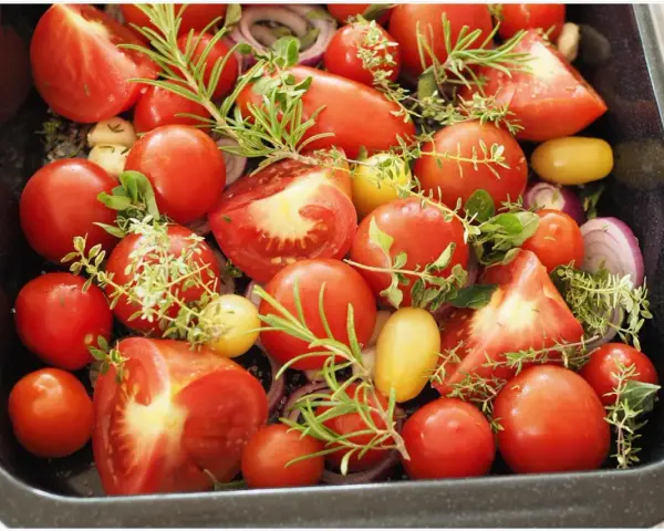 Tomaten einkochen im Backofen: Frische Tomaten, Zwiebeln und Kräuter in einer Auflaufform, bereit für den Ofen.