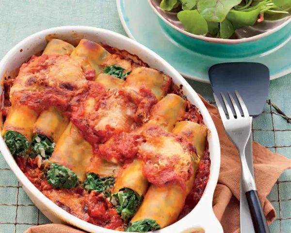 Cannelloni ricotta-spinat italienisch, überbacken mit Tomatensauce und Käse, serviert in einer Auflaufform.