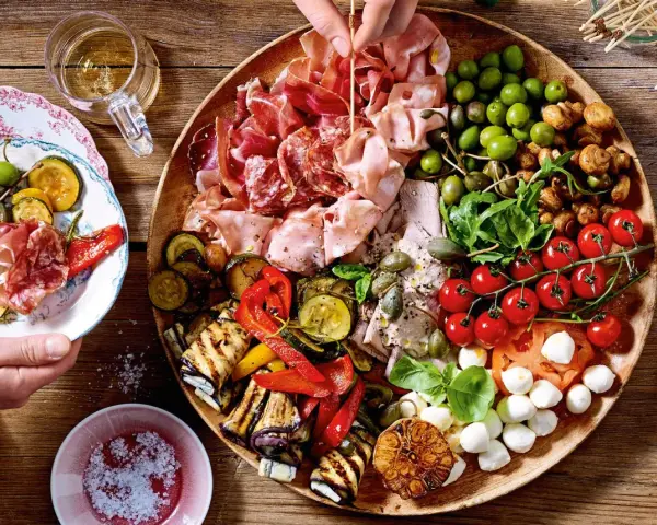 Italienische Snacks Rezepte: Eine üppige Platte mit Aufschnitt, gegrilltem Gemüse, Oliven, Tomaten und Mozzarella. Perfekt für einen Aperitif!