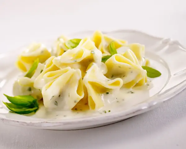 Gefüllte Pasta in cremiger Basilikum-Sahne-Sauce, garniert mit frischen Basilikumblättern. Ein Genuss für Gaumen und Auge.