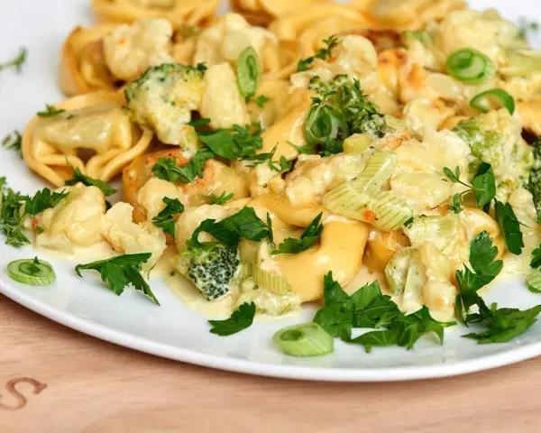 Tortellini mit Brokkoli und Blumenkohl in cremiger Sauce, garniert mit Petersilie. Lecker, wenn man Tortellini anbraten möchte.