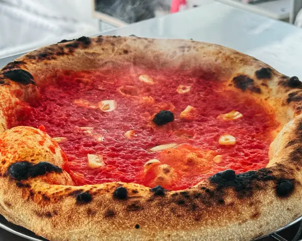 Heiß dampfende Pizza mit knusprigem Rand und leckerer marinara sauce, belegt mit Knoblauch und Oliven.
