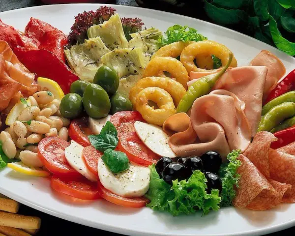 Eine üppige antipasti platte mit Schinken, Salami, Oliven, Artischocken, Tomaten-Mozzarella-Salat und frittierten Ringen.