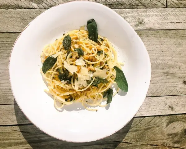 Spaghetti in Salbeibutter mit Parmesan und Walnüssen, garniert mit frischen Salbeiblättern.