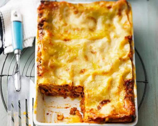 Ein frisch gebackenes, goldbraunes Lasagne-Rezept, original italienisch, mit einer Portion entnommen.
