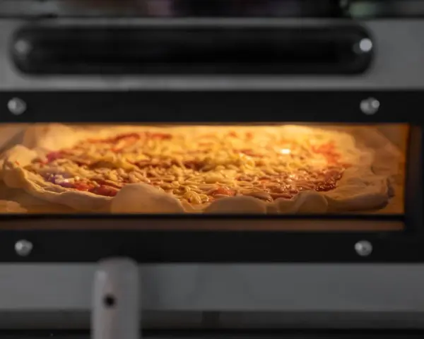 Eine Pizza mit Käse und Tomatensauce backt in einem Ofen.