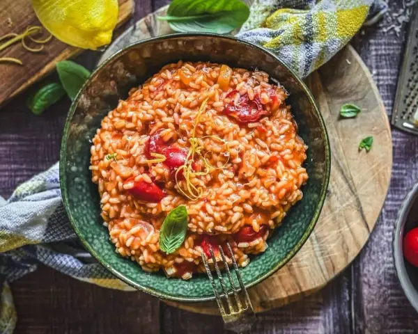 Cremiges Tomaten-Risotto, ein einfaches und köstliches Risotto Rezept, garniert mit Basilikum und Zitronenzeste.